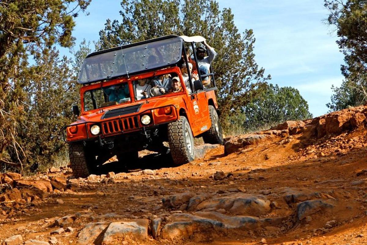 una jeep arancione che guida su una strada sterrata