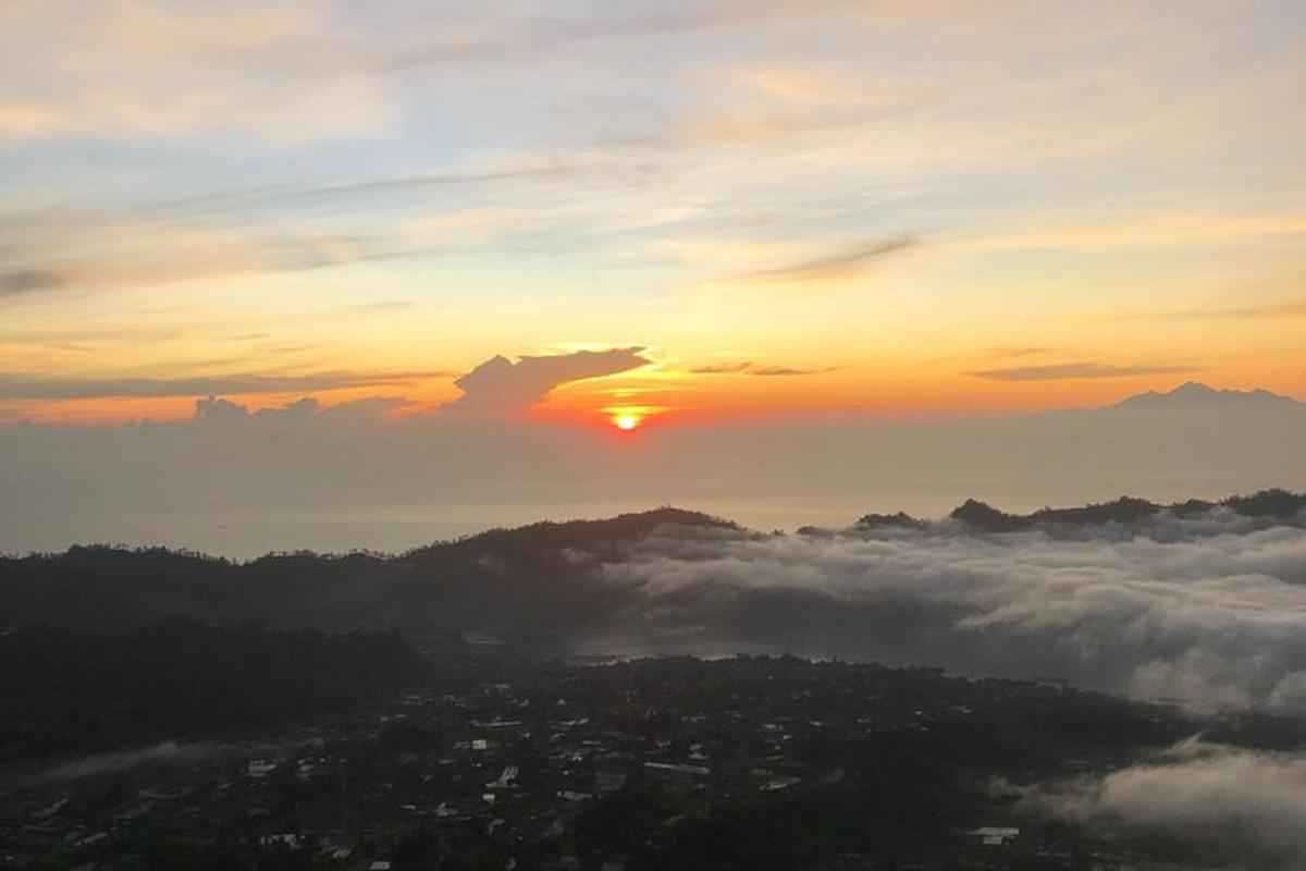 Una puesta de sol sobre una ciudad con un montón de nubes.