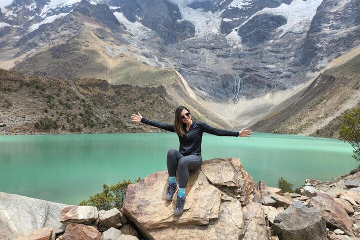 seorang wanita duduk di atas batu di hadapan gunung