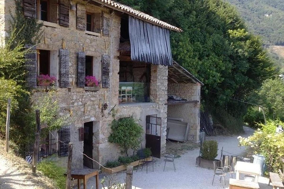 Una antigua casa de piedra con mesas y sillas delante de ella.