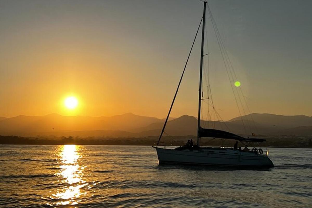 a sail boat in the water at sunset