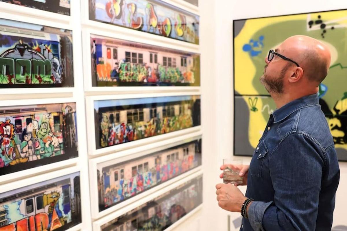 un home mirant obres d'art en una paret