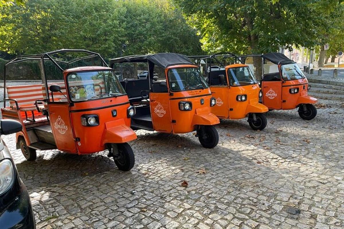 Na ulici jsou zaparkované tři oranžové golfové vozíky