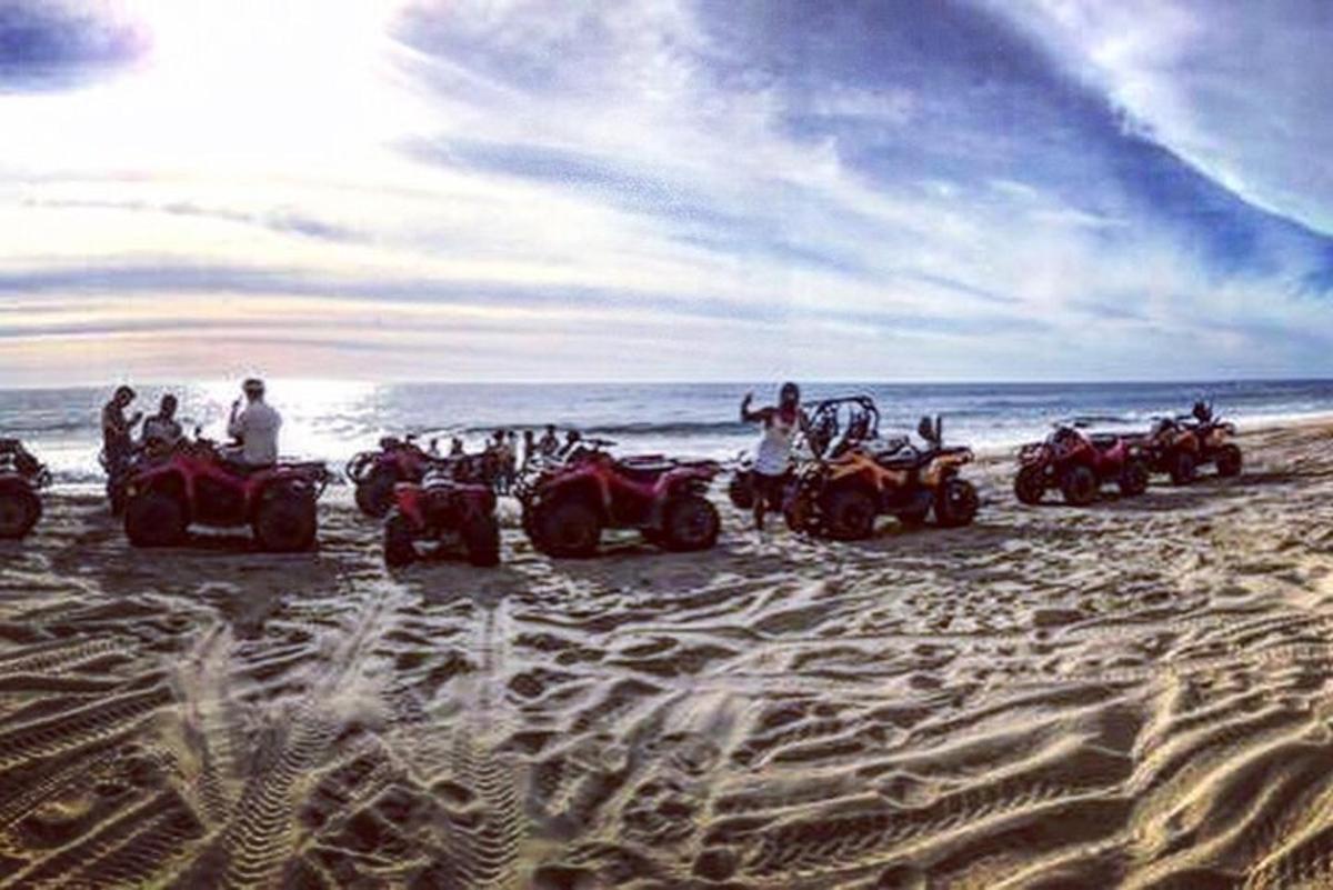 Un grupo de personas conduciendo vehículos todo terreno en la playa.