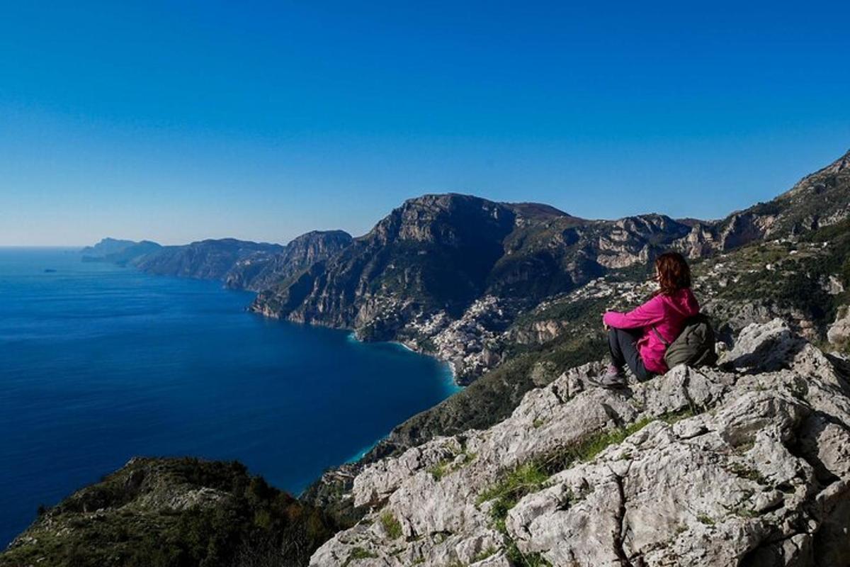 una donna seduta in cima a una montagna che domina l'oceano