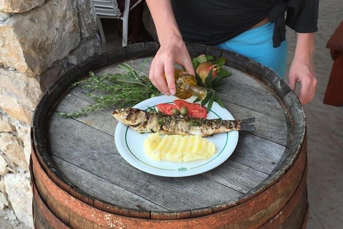 una persona sosteniendo un plato de pescado y fruta en un barril