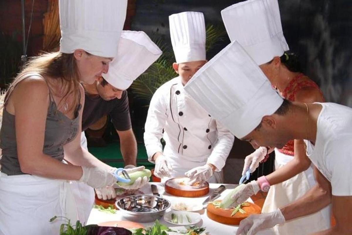 um grupo de chefs em pé ao redor de uma mesa preparando comida