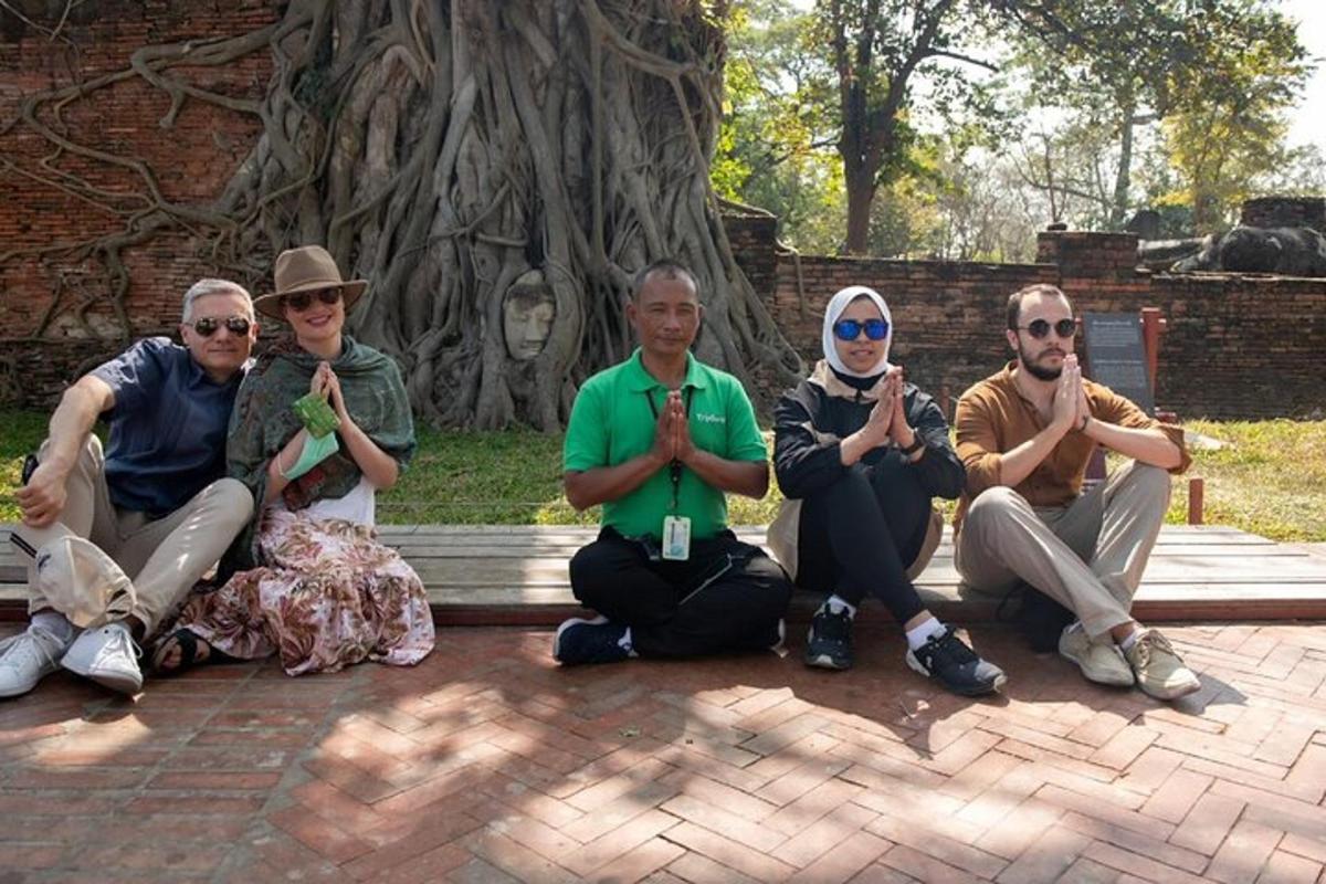 sekumpulan orang duduk di bangku di hadapan pokok
