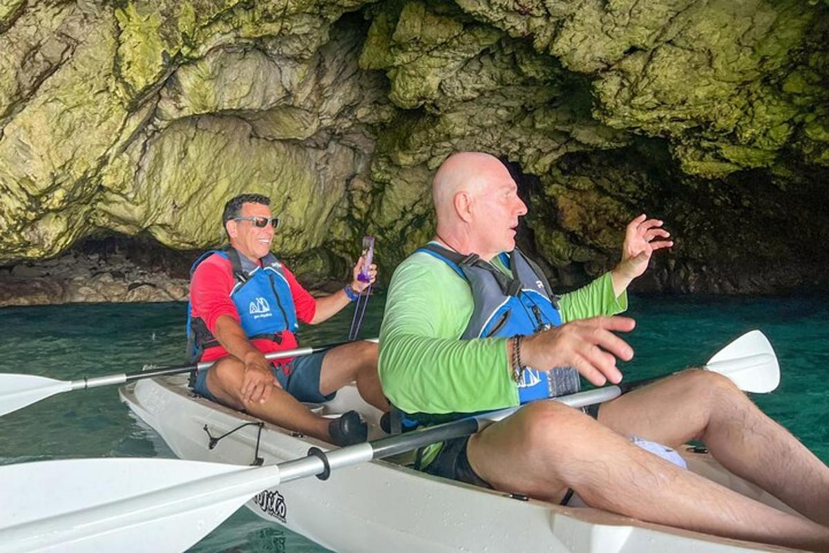 dua lelaki menaiki kayak di hadapan sebuah gua