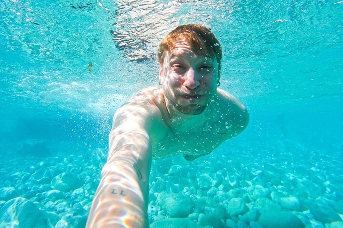 seorang lelaki sedang berenang di dalam air biru