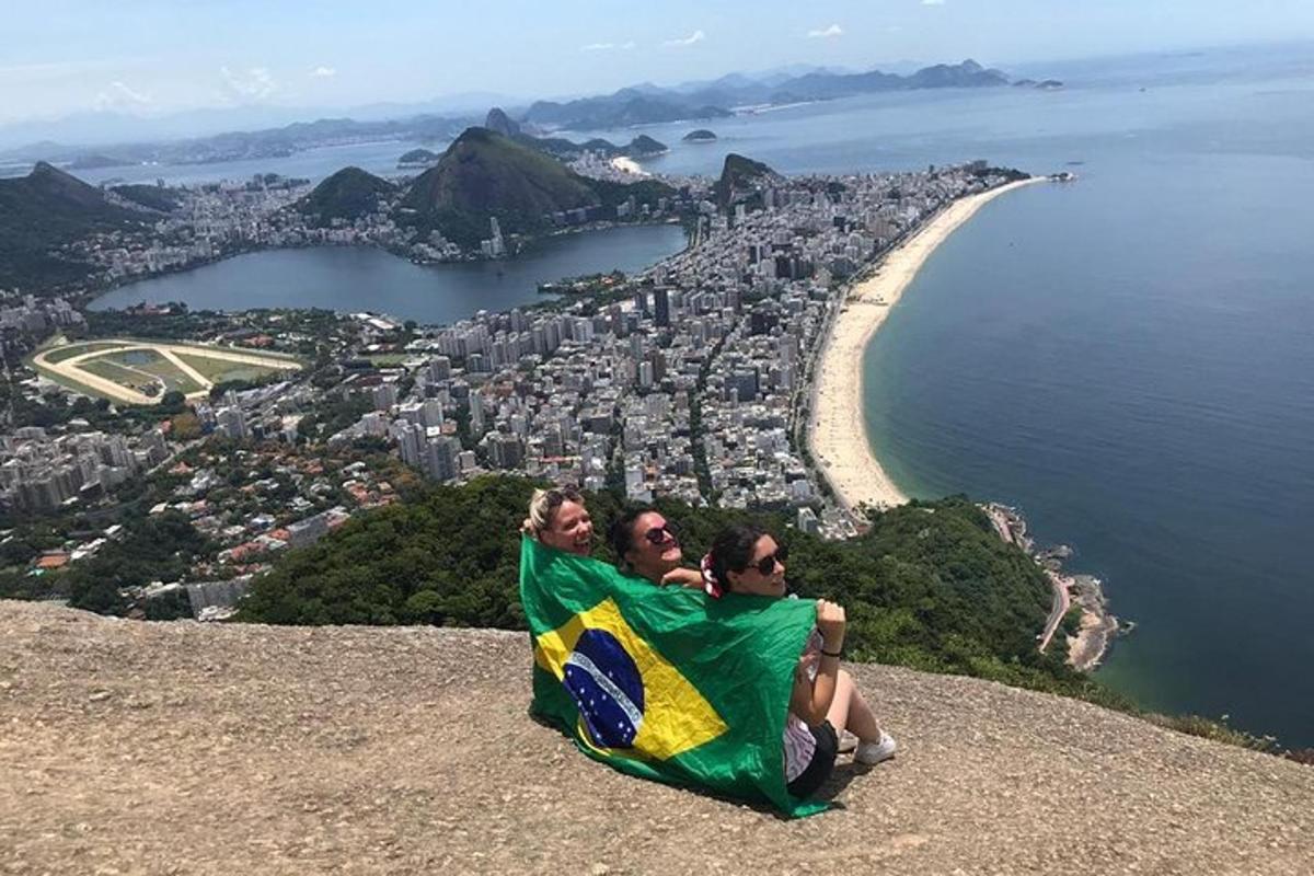 duas pessoas sentadas no topo de uma colina segurando uma bandeira