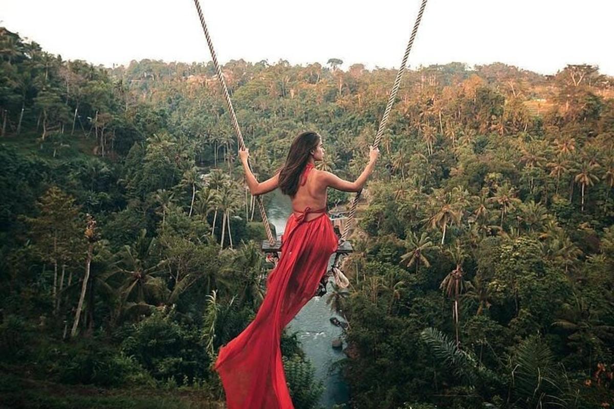 una donna con un vestito rosso che si dondola su un ponte sospeso