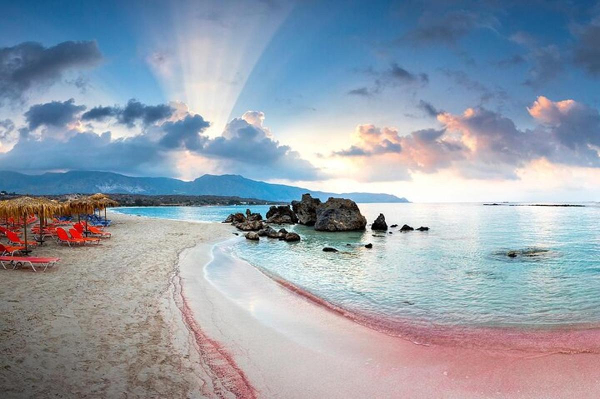 een strand met roze zand en rotsen in het water