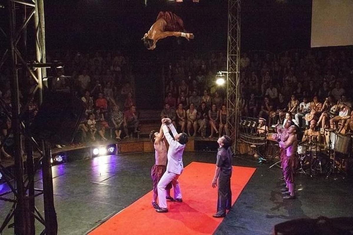 egy csoport ember cirkuszi színpadon, egy ugró személlyel
