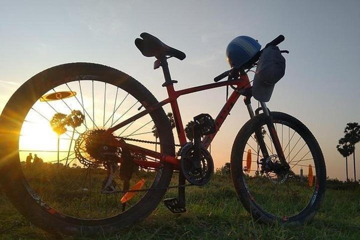 una bicicleta aparcada en un camp amb la posta de sol al fons