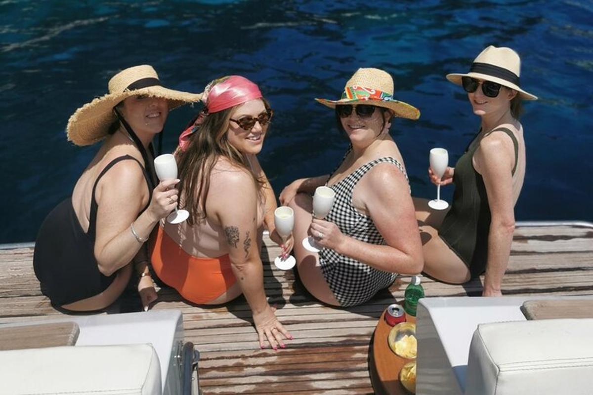 un gruppo di donne con cappelli sedute su un molo con un gelato