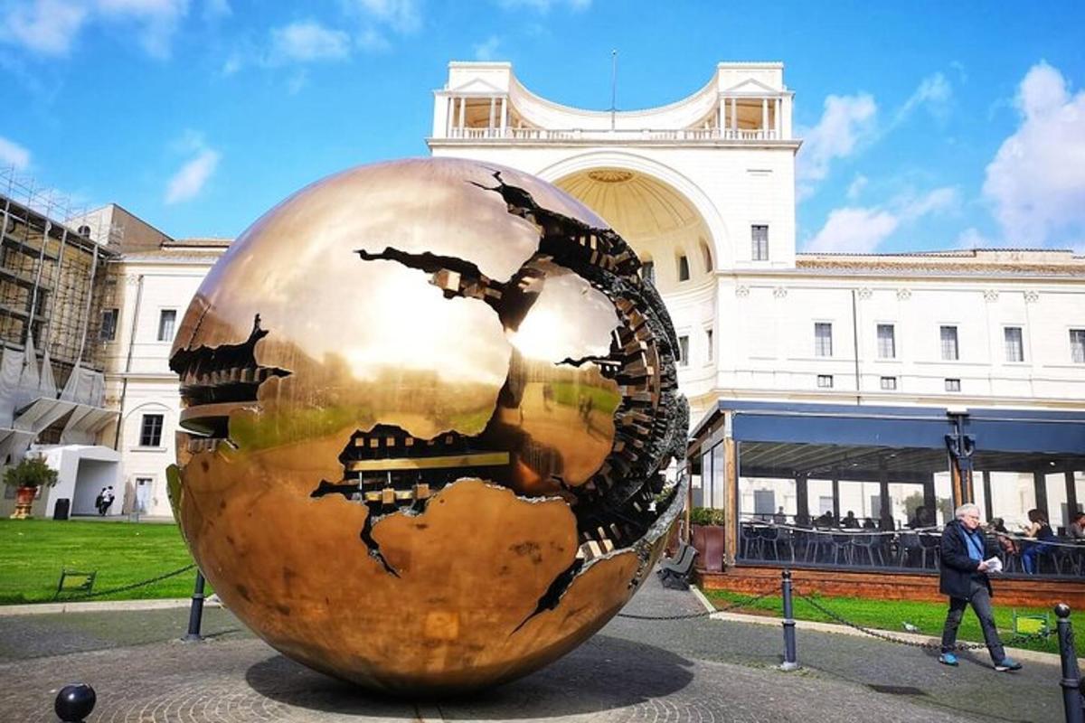 una grande scultura a forma di globo dorato di fronte a un edificio