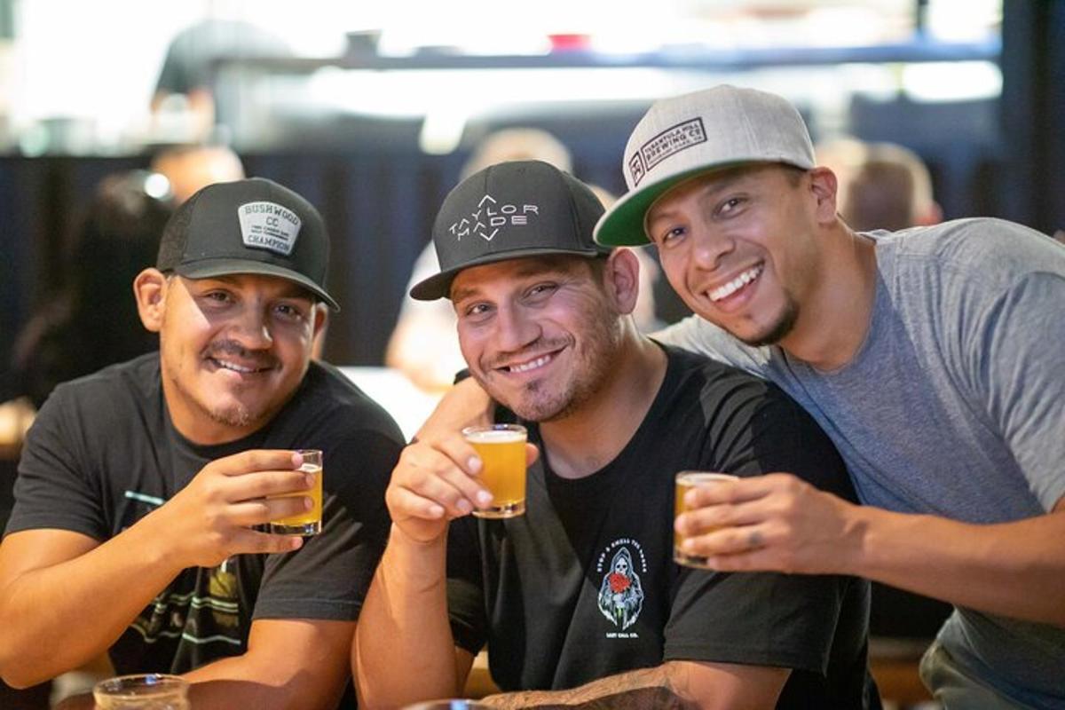 drei Männer sitzen an einem Tisch und trinken Bier