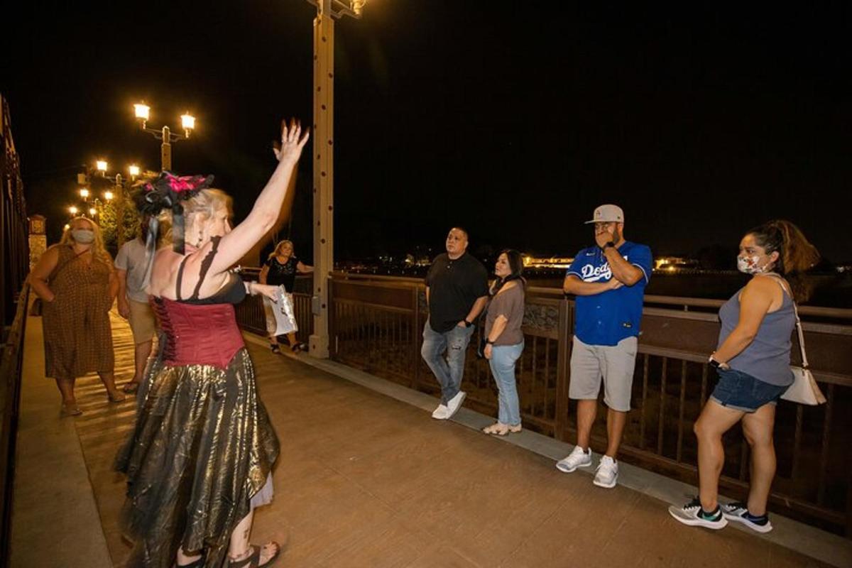 eine Frau, die mit der Hand in der Luft auf einer Brücke steht