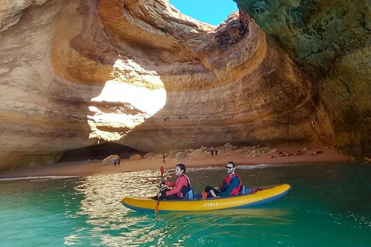 two people in a kayak in the water near a cave