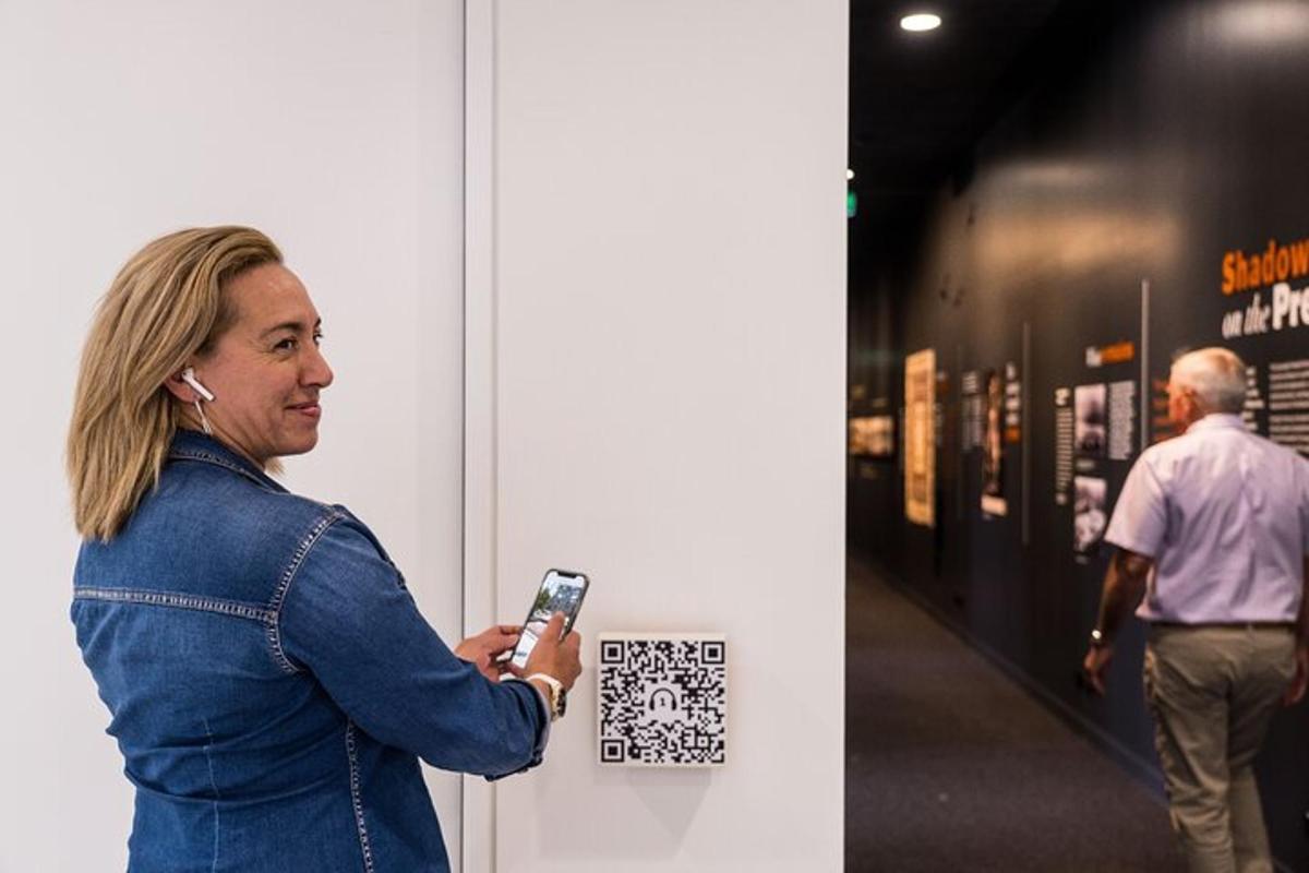 a woman standing next to a wall holding a cell phone