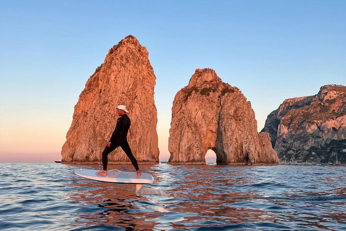 a person riding a surfboard in the water with a rock formation