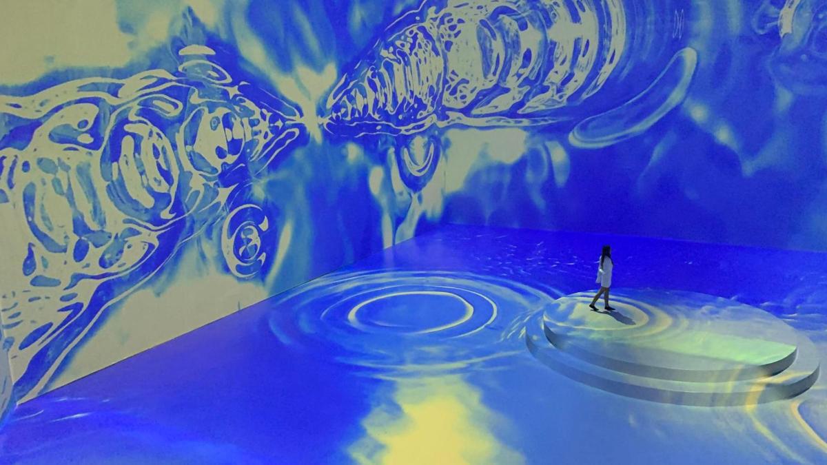a person standing in front of a painting of two jellyfish