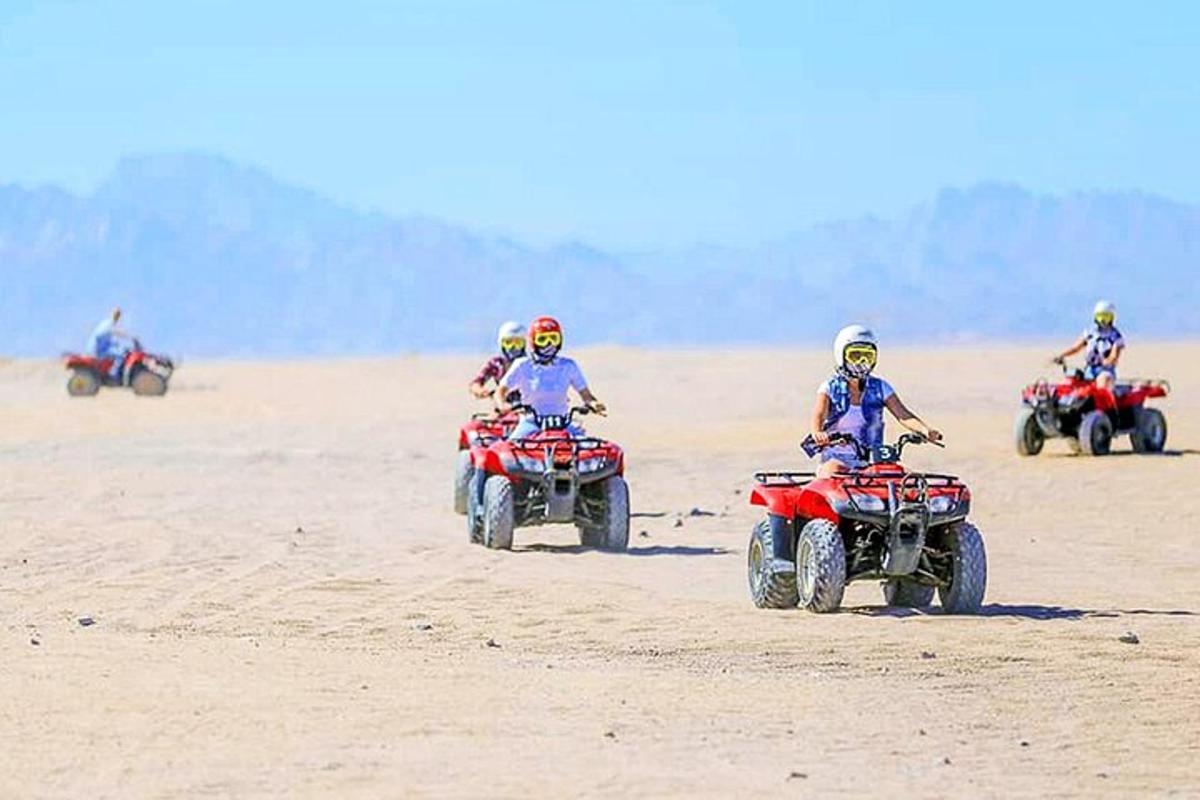 sekelompok orang mengendarai ATV di pasir