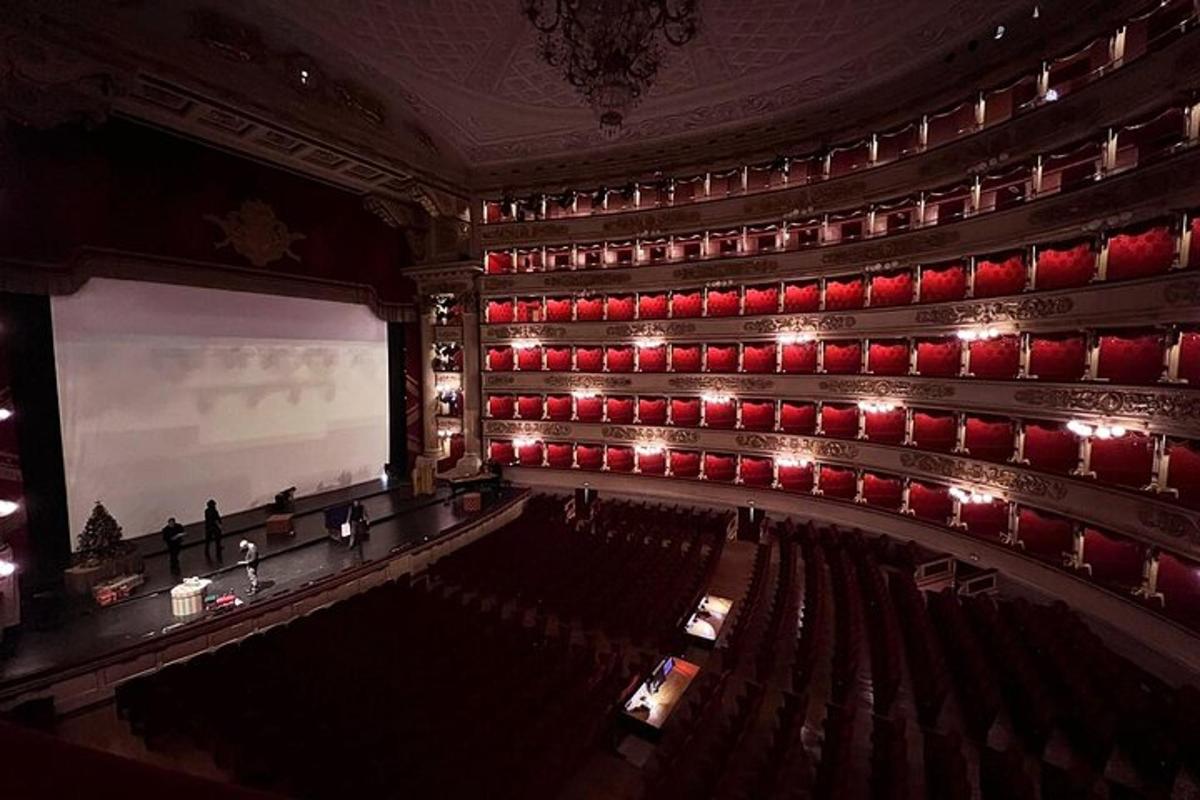 Un auditorio vacío con sillas rojas y una pantalla.
