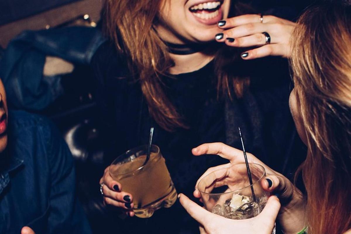 飲み物を手に持ちながら笑っている2人の女性