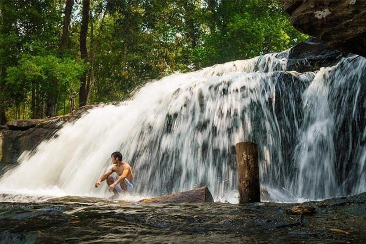 un bărbat stă în fața unei cascade