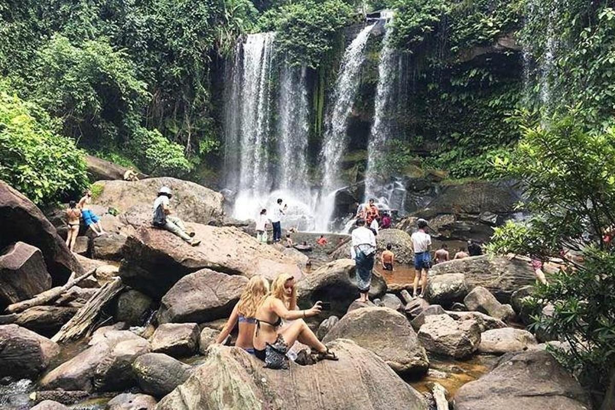 un groupe de personnes assises sur des rochers devant une cascade