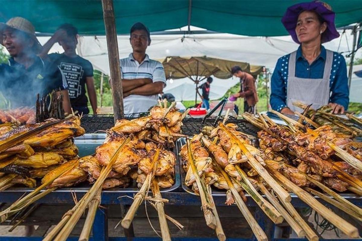 một nhóm người đứng quanh một lò nướng với đồ ăn