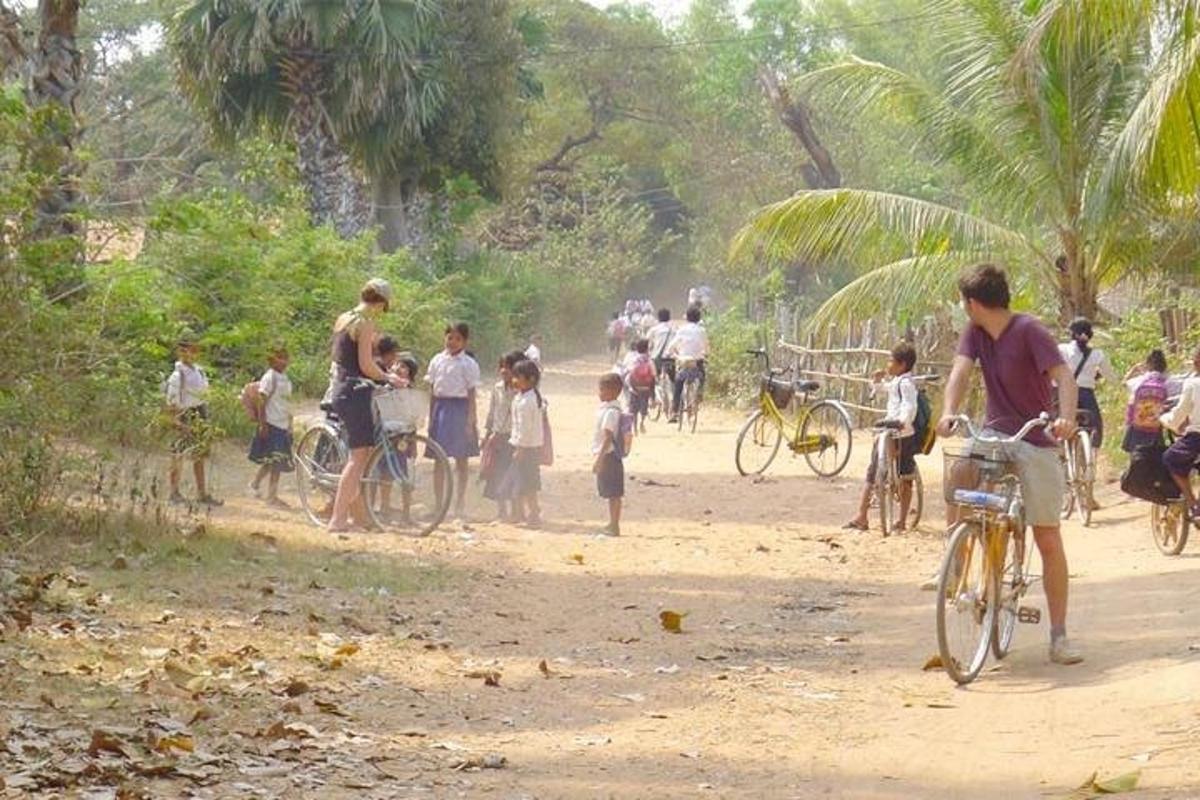 skupina ľudí na prašnej ceste s mužom na bicykli