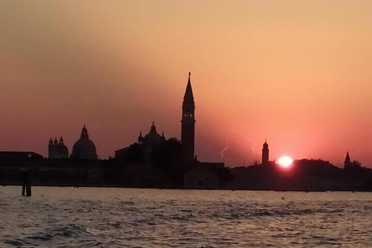 una posta de sol sobre una ciutat amb una torre del rellotge