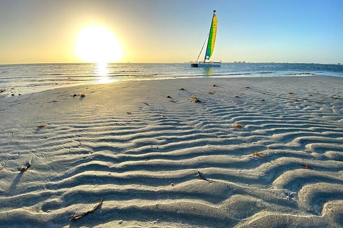 pantai berpasir dengan bot layar di lautan