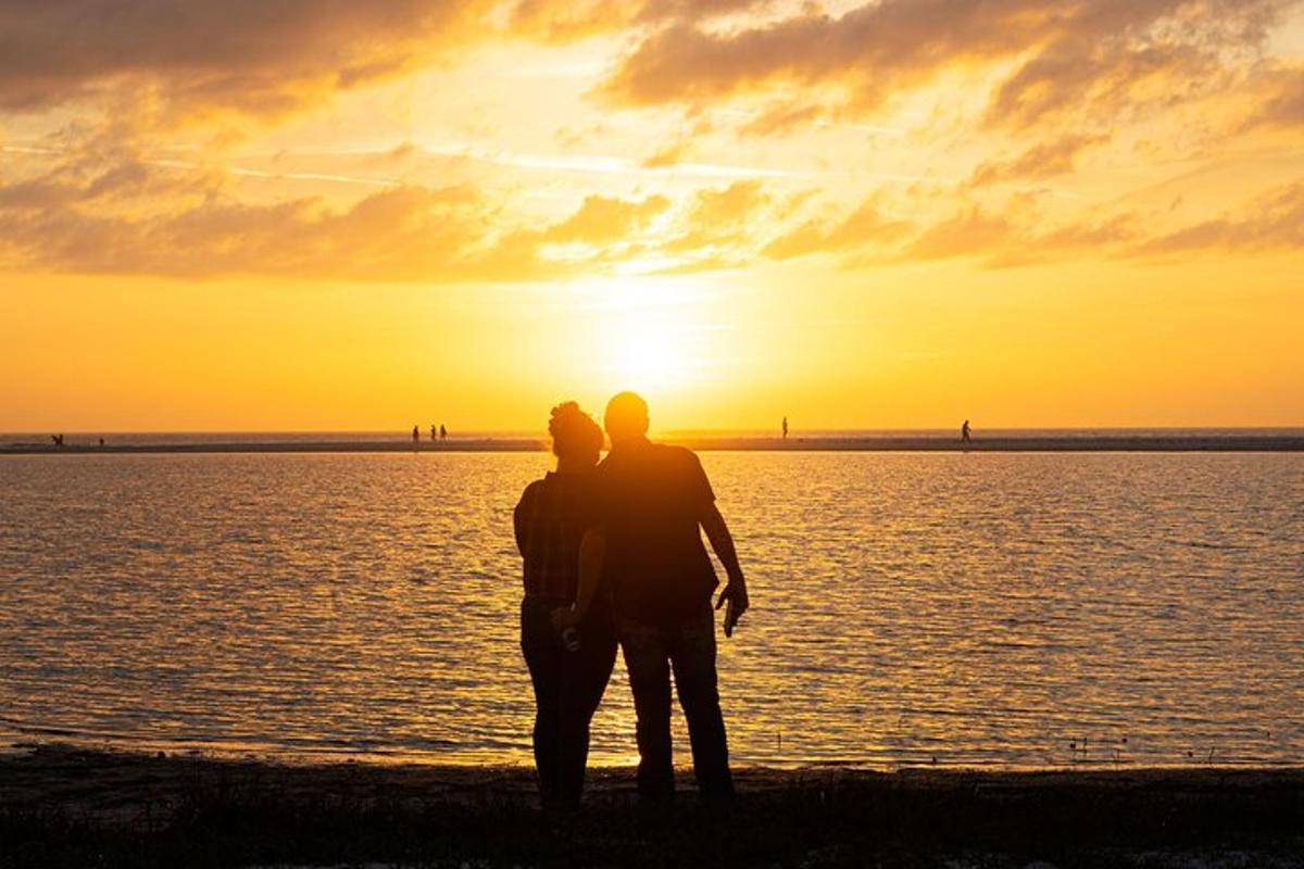 moški in ženska stojita na plaži ob sončnem zahodu