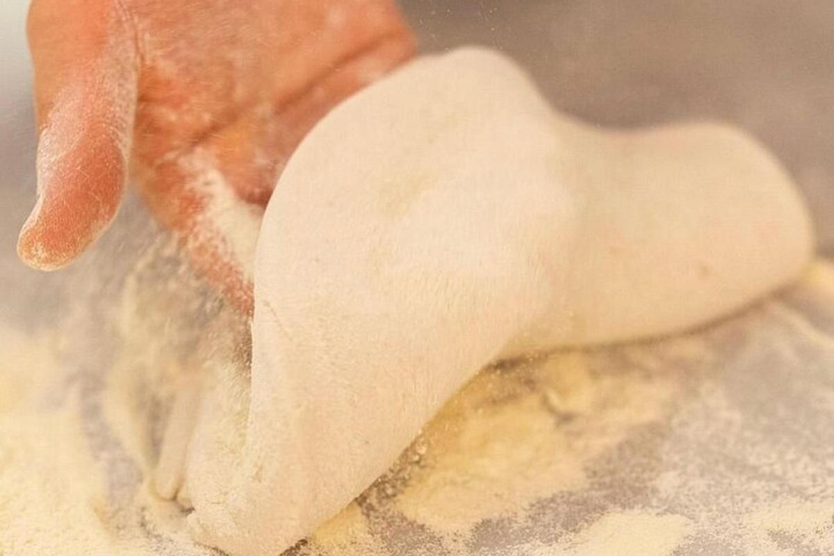 una persona che tiene in mano un pezzo di impasto in una ciotola