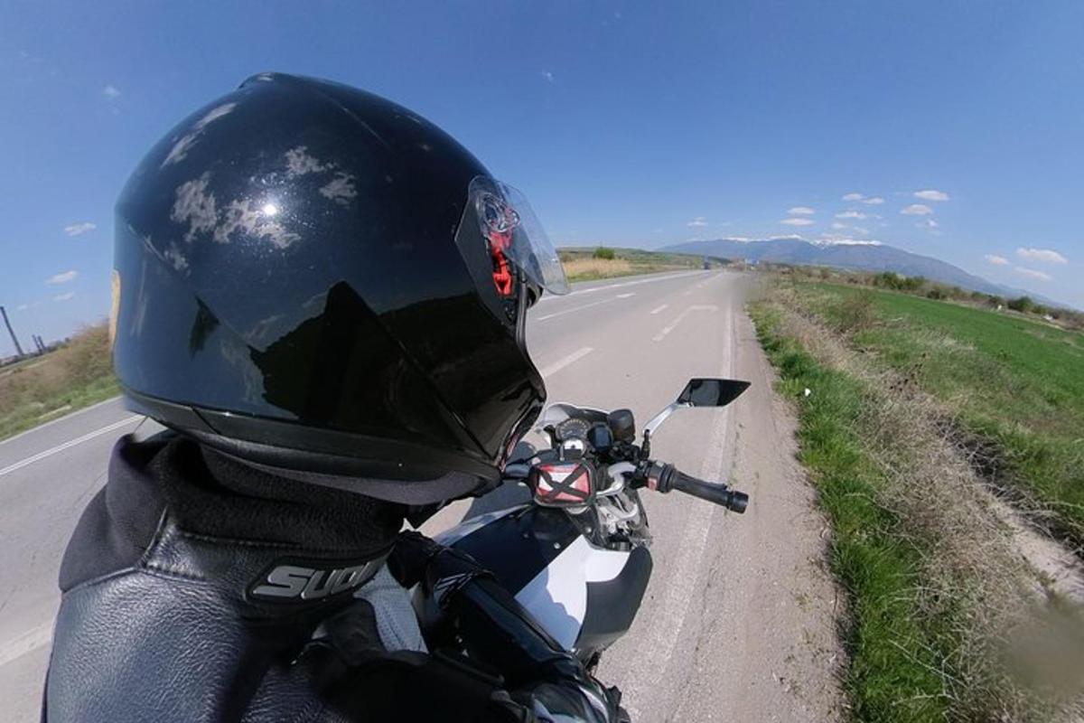 osoba s helmou jedoucí na motorce po silnici