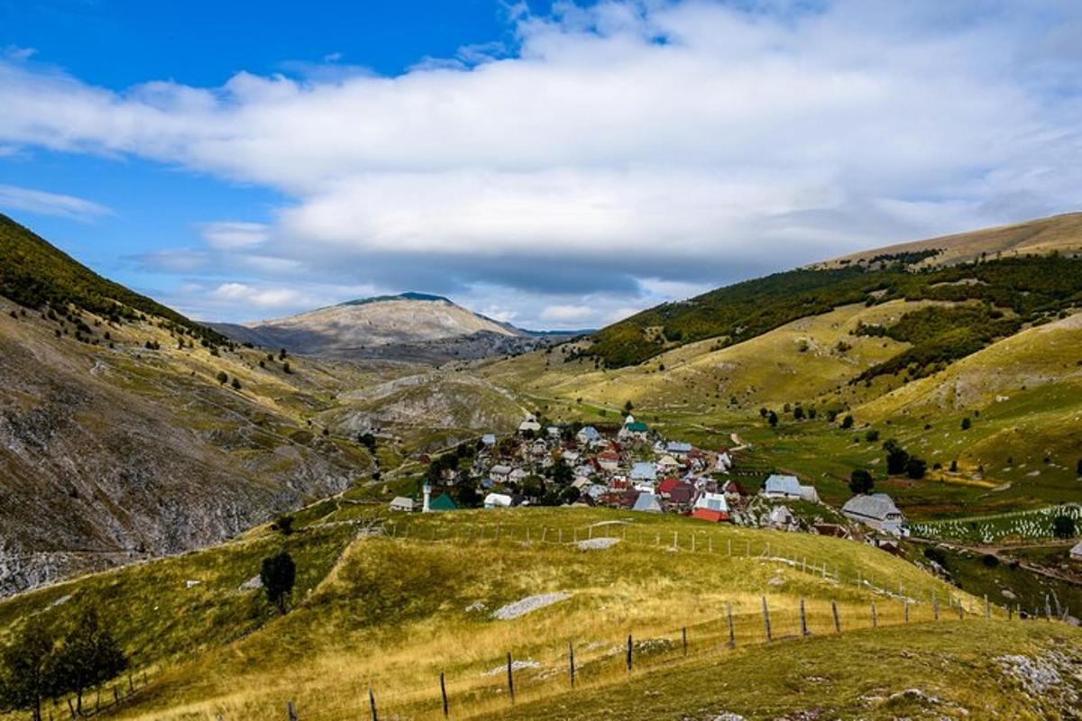 un pueblo en una colina con montañas al fondo