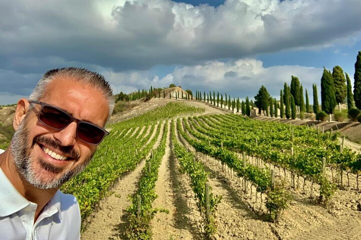 a man in sunglasses standing in front of a vineyard