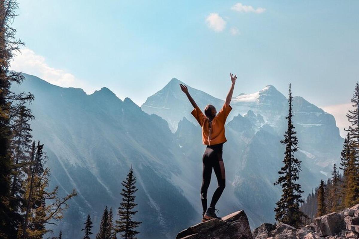 seseorang yang berdiri di atas gunung dengan tangan di udara