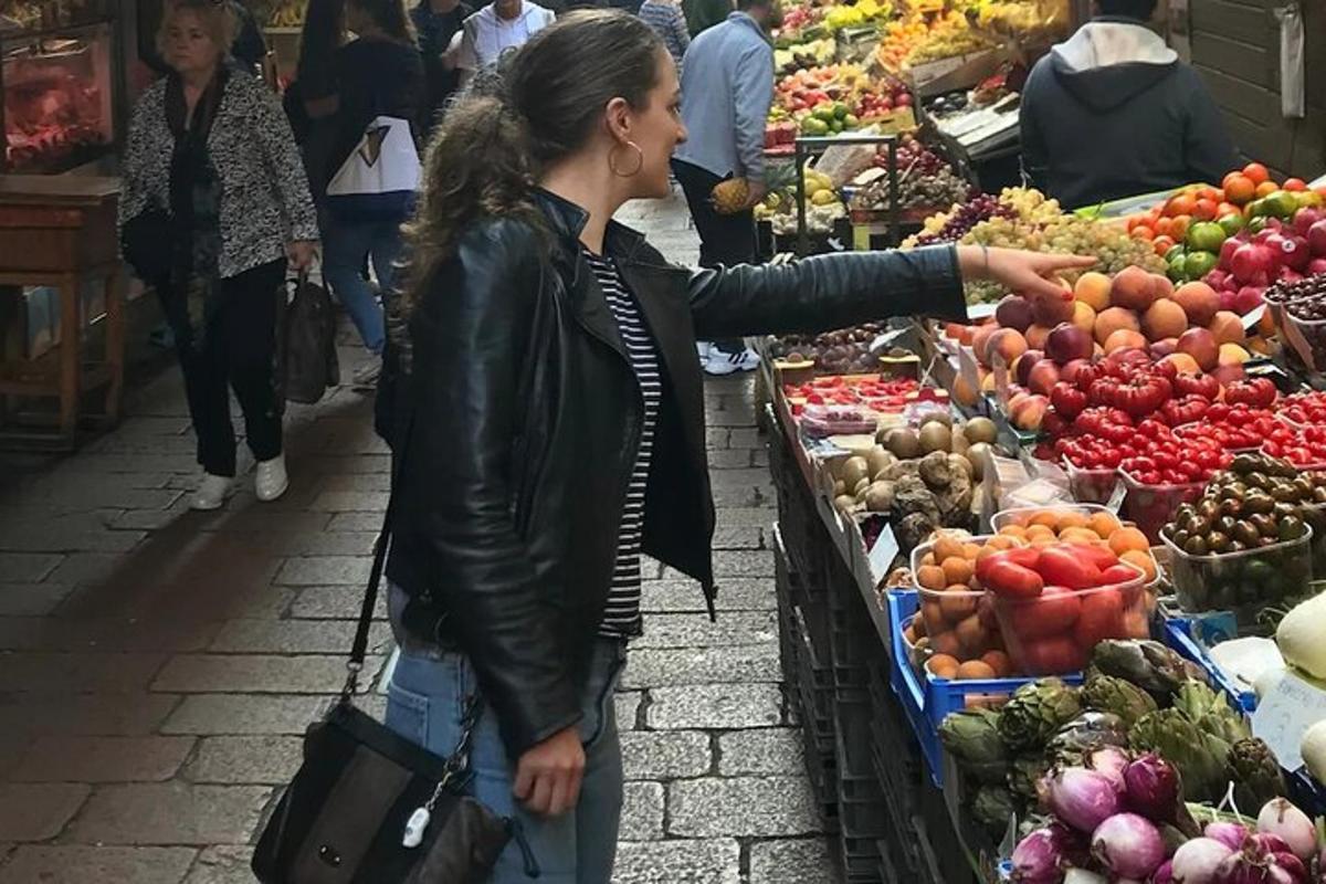 naine seisab turul ja osutab köögiviljadele
