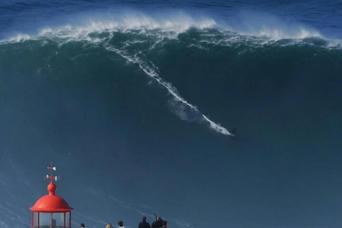 a large wave in the ocean with a red lighthouse