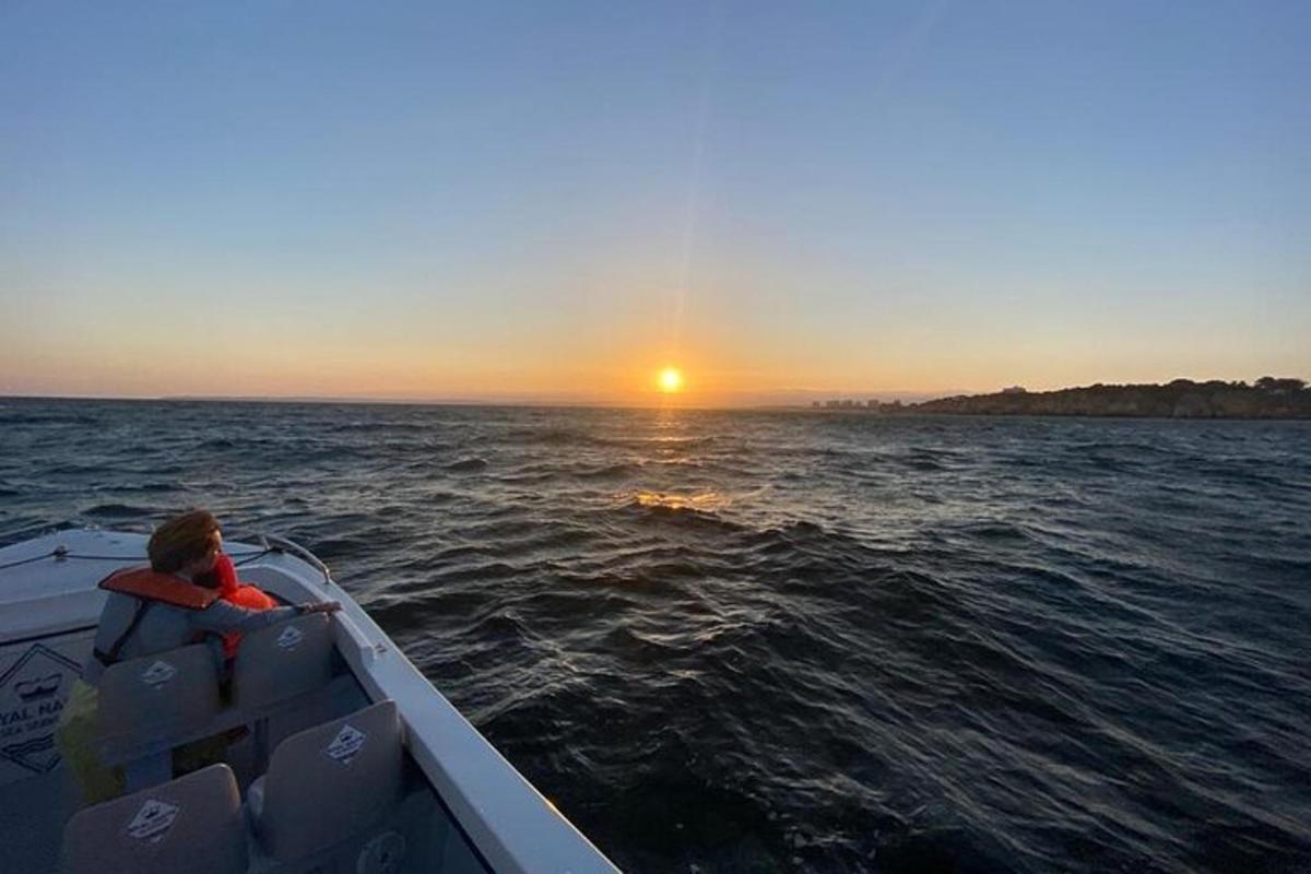 a man on a boat in the water at sunset