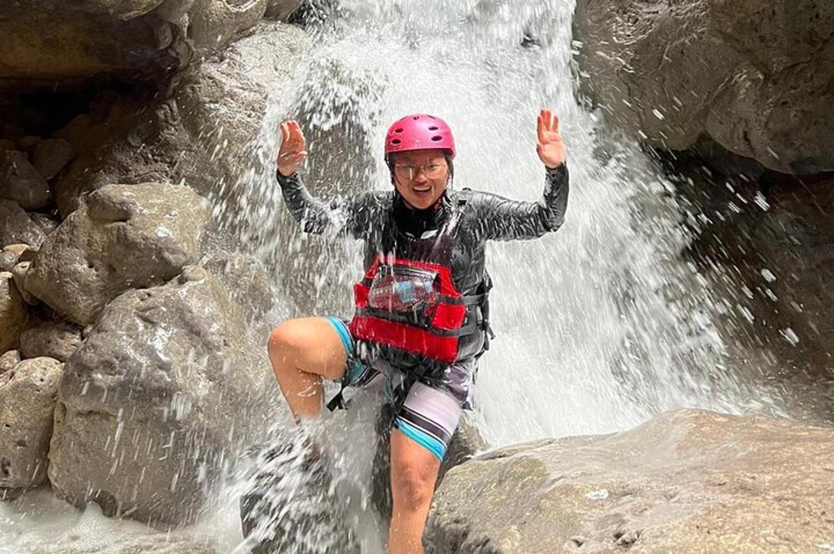 Una mujer con casco parada frente a una cascada.