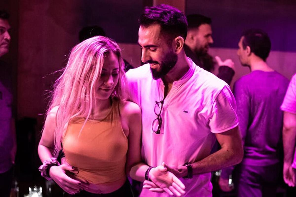 un bărbat și o femeie stând într-o cameră cu lumini roz