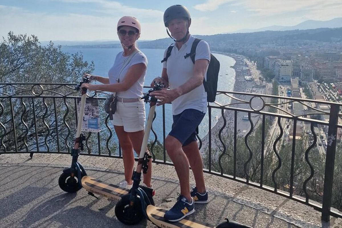 a man and a woman standing on scooters on a ledge