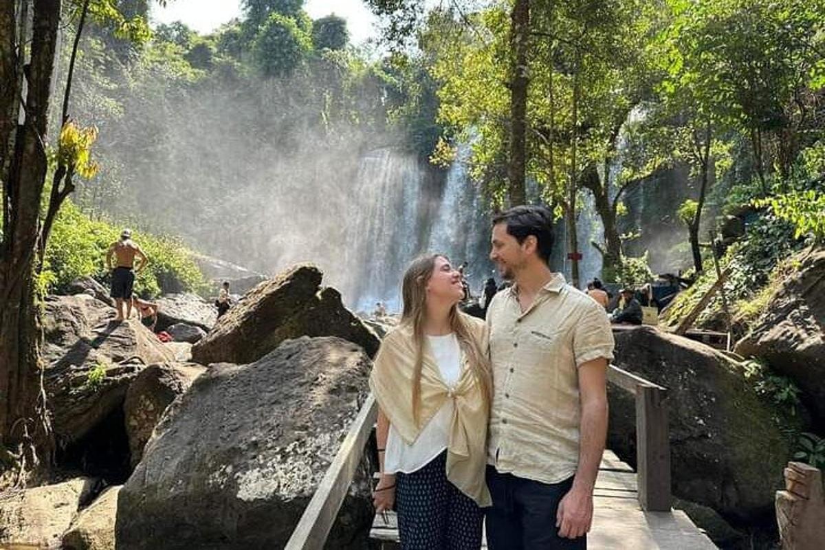 Un hombre y una mujer de pie frente a una cascada
