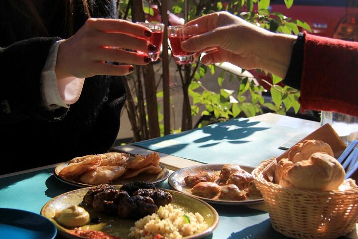 a person holding a glass of wine over a table with plates of food